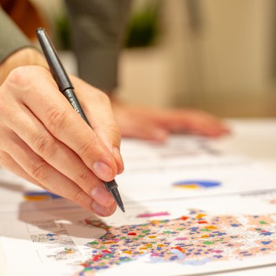 Hand holding a pen marking a map of the United States.